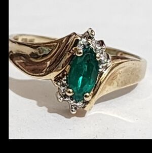 10 KT gold marquess emerald ring with little round diamond accents.